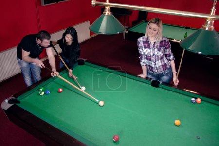 Man is teaching his friends how to play billiard