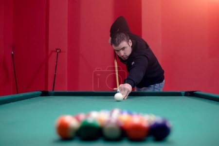 Attractive young man is playing billiard