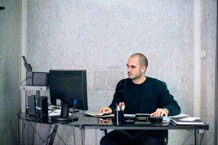 Vue de face de l'homme d'affaires sérieux travaillant dans le bureau, en utilisant PC de bureau.
