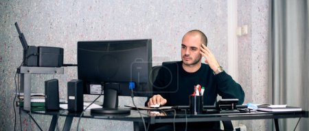 Besorgter Geschäftsmann schaut und hält Computermonitor und Kopf in den Händen.