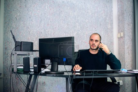 Photo for Young worried businessman in his office, getting bad business news on his mobile phone. - Royalty Free Image