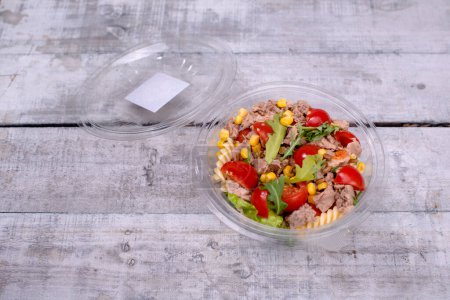 High angle view of tuna salad in opened bowl on grey background.