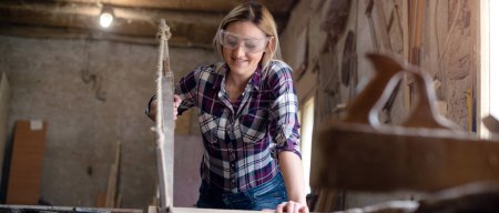 Photo for Young attractive blond woman is working in carpenter workshop - Royalty Free Image