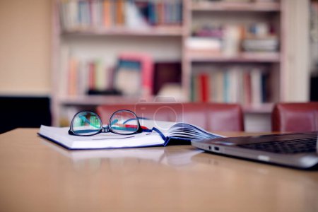 Photo for Laptop, opened notebook and eyeglasses at desk in home office. - Royalty Free Image