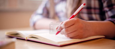 Ausschnitt einer Studentin, die am Schreibtisch lernt und sich auf die Schulprüfung vorbereitet.
