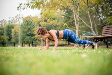 Photo for Side view of woman doing push-ups in park. - Royalty Free Image
