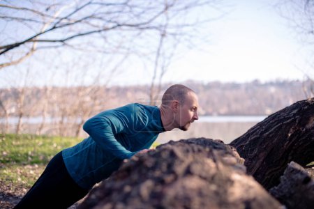 Photo for Man doing push ups outdoors, side view. - Royalty Free Image