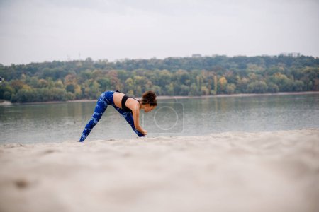 Beautiful woman exercising on sand.
