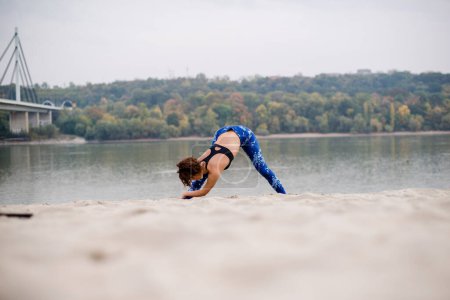 Photo for Young beautiful woman stretching on the sand. - Royalty Free Image