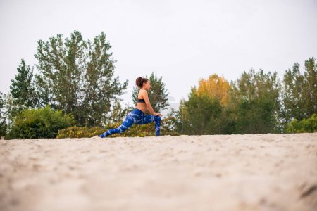 Photo for Woman enjoying stretching her legs outdoors, on the beach. - Royalty Free Image