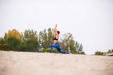 Photo for Young woman finishing her sports training, doing stretching exercises on the beach. - Royalty Free Image