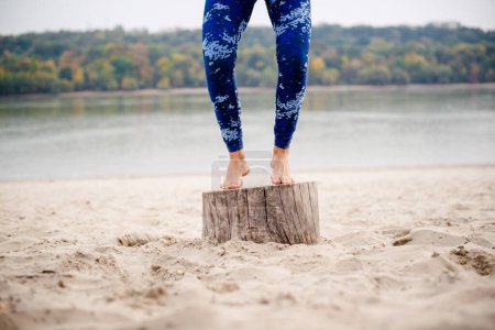 Photo for Woman jumping on the stump, low section, sand and water also. - Royalty Free Image