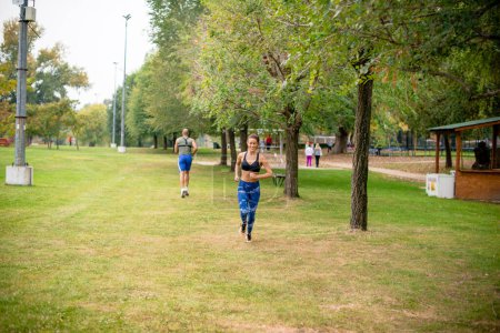 Young woman and man running in public park, on footpath.