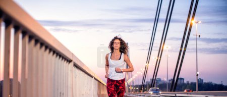 Young caucasian woman running on the bridge, front view.
