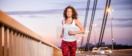Young caucasian woman running on the bridge, front view.
