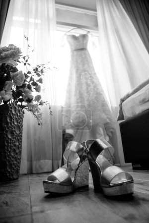 Black and white photo of glamour shoes and wedding dress
