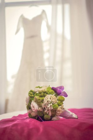 Bouqet de boda en una cama delante del vestido de novia