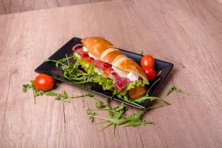 Nice decorated plate with delicious sandwich on the wooden table