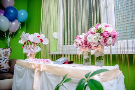 Hochzeitstisch mit Blumen, rosa Strauß Rosen und Schleife und Luftballons.