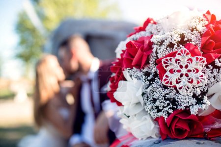 Téléchargez les photos : Gros plan de fleurs de mariage, mariée et marié baisers en arrière-plan. - en image libre de droit