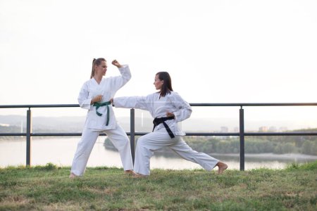 Two karate woman fighting on outdoor.