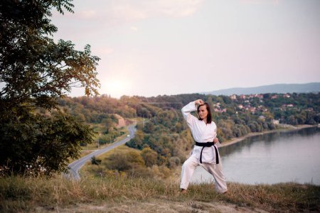 A young karate professional practicing while wearing a black belt.