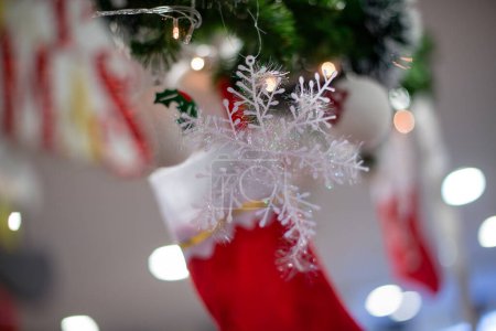 Flauschige rote Socke und künstliche Schneeflocke am Weihnachtsbaum, Nahaufnahme.