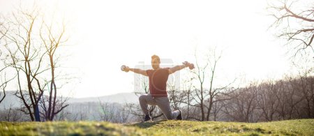 Mann trainiert in der Natur mit Gewichten Panorama, Bergblick