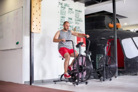 Young man is exercising on bicycle in gym