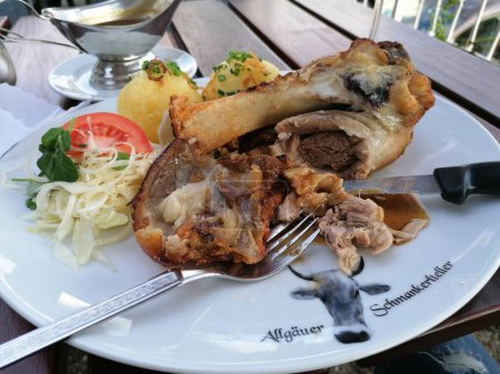 Tasty Pork Knuckle with potatos and sauerkraut on the side. High quality photo