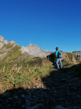 Women hiking in the mountains with backpack looking at santis. Swiss Alps. Appenzellerland. . High quality photo