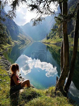Mujeres senderismo en los Alpes suizos, Appenzellerland, Alpstein, silouhette con Falensee en la parte posterior y hermoso reflejo de las montañas y las nubes. Foto de alta calidad