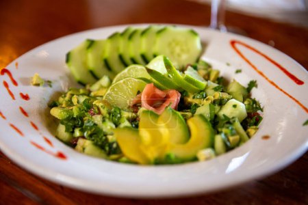 Photo for Avocado cucumber salad with a siracha design on the plate and ginger - Royalty Free Image