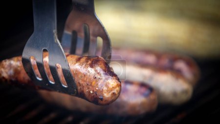 Photo for Grabbing sausage off the grill during a Bar B Q - Royalty Free Image
