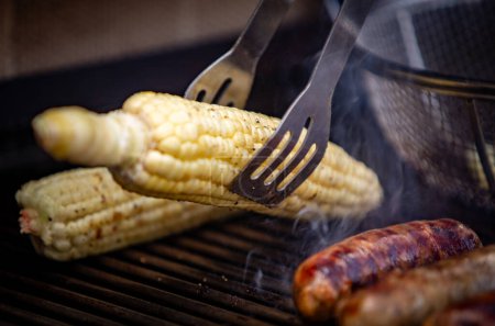 Photo for Grabbing corn on the grill with sausage being cooked - Royalty Free Image