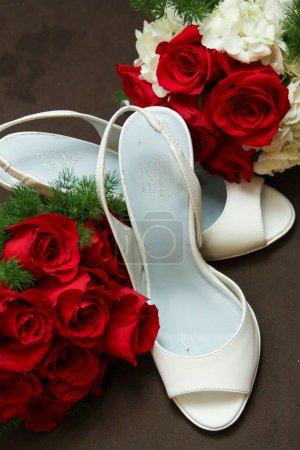 Rote Rosen und weiße Brautschuhe