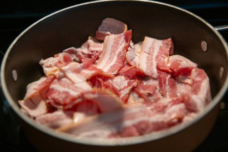 Cooking bacon on a stove top in a pot
