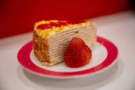 Layered Strawberry Crepe Cake garnished and drizzled with sauce