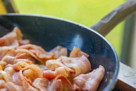 Bacon sizzling in a pan outdoors
