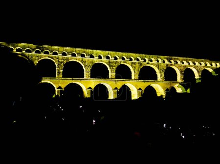 night photo of the Pont du Gard which is located in the south of France. ancient Roman aqueduct. majestic famous bridge that attracts tourists from all over the world. architectural work illuminated by lights.