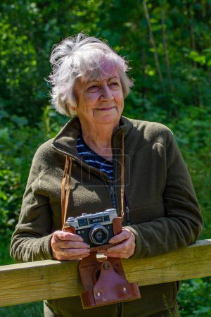 Téléchargez les photos : Bovey Tracey, Devon Royaume-Uni. 4 juillet 2022. Femme âgée photographe sur un oiseau, séance photo de la nature. Utilisant un vieux FED 4 russe, appareil photo de l'URSS. Pose détendue, Vie aînée. - en image libre de droit