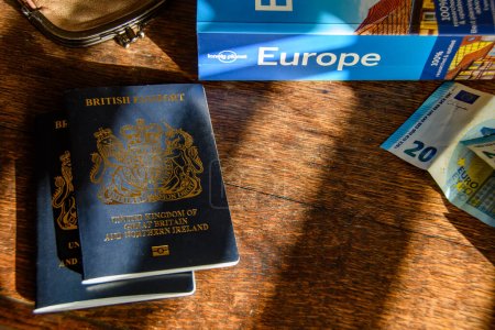 Photo for Exeter UK. 11-19-23 European  travel money, passport and trip planning image. Essentials for Vacation and holidays. British passport, Euro's and travel guide book sat on a table.  City break tour. - Royalty Free Image