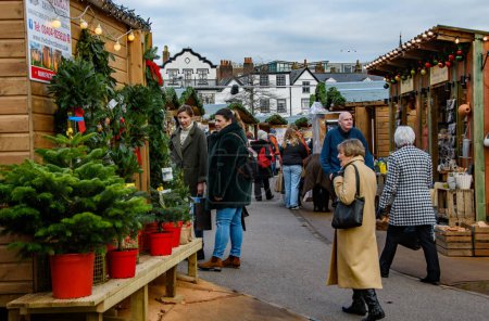 Téléchargez les photos : Exeter UK. 11-28-23. Acheteurs au marché de Noël d'Exeter. personnes marchant pendant le marché de Noël admirant étal de marché, acheter de la nourriture, des cadeaux et des jouets. décorations lumineuses pendant l'hiver. - en image libre de droit