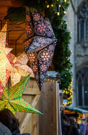 Téléchargez les photos : La lanterne en forme d'étoile est illuminée dans un étal de marché de Noël. Décorations lumineuses colorées à vendre. - en image libre de droit