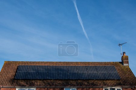 Téléchargez les photos : Panneaux solaires sur un toit de maison sous un grand ciel bleu. - en image libre de droit
