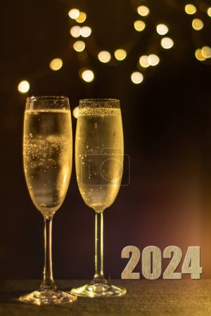 Photo for 2024 image with two glasses of frosted Champaign against a soft party light bokeh background. Selective focus on the right hand frosted glass. - Royalty Free Image