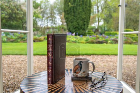 Photo for Newton St Cyres, Devon, uk. 04-30-23.  A tale of two cities book by Charles Dickens. Classic novel in sharp selective focus set against a softly focused garden scene, Copy space. - Royalty Free Image