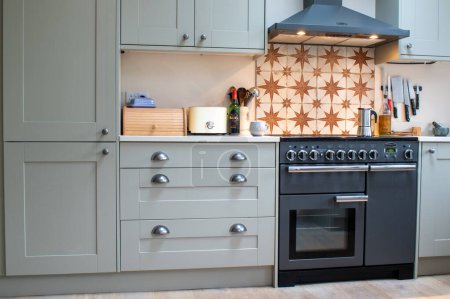 Photo for Diptford, Devon, uk. February 2nd 2023. Rangemaster stove cooker with cooker hood and matching cabinets on either side. Food preparation in a modern but country kitchen. Copy space. - Royalty Free Image