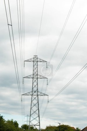Foto de Pilones de electricidad contra un cielo blanco nublado. Pilón gris grande con cable de tierra y conductores eléctricos. Parte de la Red Nacional de suministro de energía en todo el país. Alto voltaje. Torre peligrosa - Imagen libre de derechos