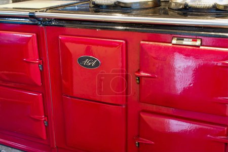 Photo for Ideford, Devon, uk. September 7th 2022. Aga range cooker in bright red. Country kitchen range oven in close up. Aga logo on the front. Iconic stove in an English farmhouse kitchen. Food preparation. - Royalty Free Image